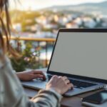Digitale Nomadin arbeitet mit Laptop auf einer sonnigen Terrasse